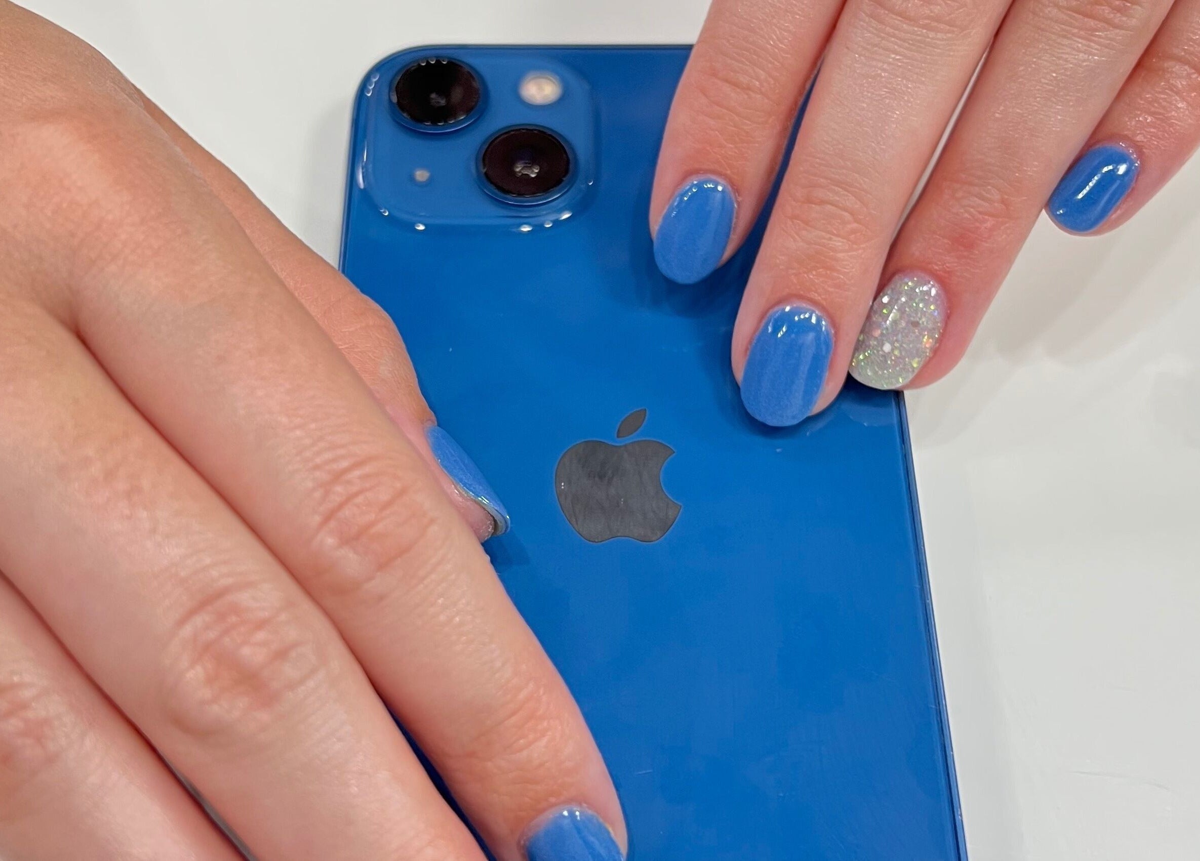 Blue manicure on hands holding a phone at Eversaint Salon in New Orleans, Louisiana, US.