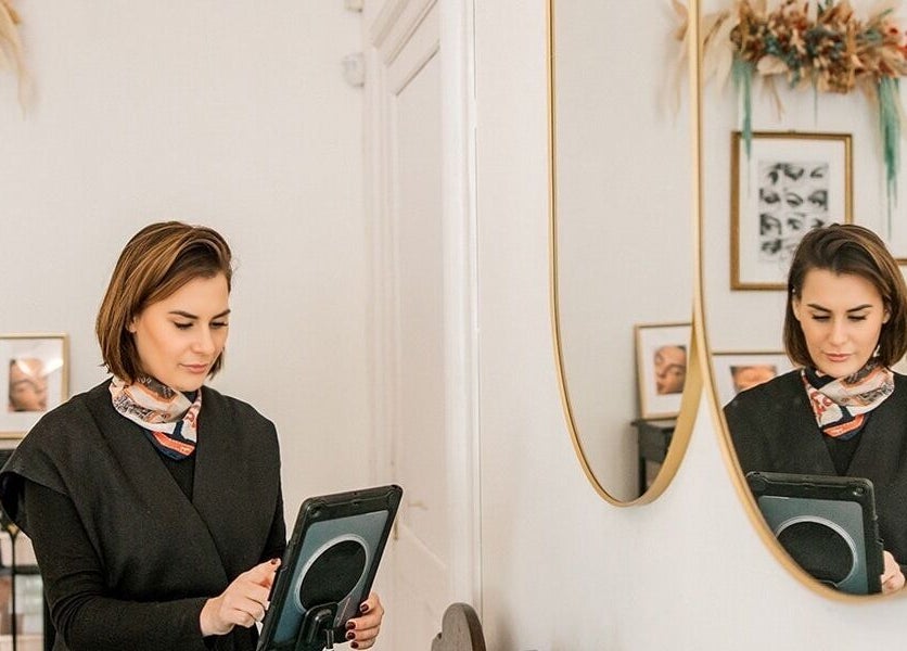 A stylist at Miss Highbrow Semi-Permanent Make-up, Lash and Brow Studio, Glasgow, Scotland, GB, using a tablet.