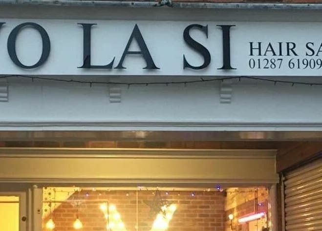 Front view of Vo La Si hair salon in Guisborough, England, GB with illuminated signs and cozy ambiance.