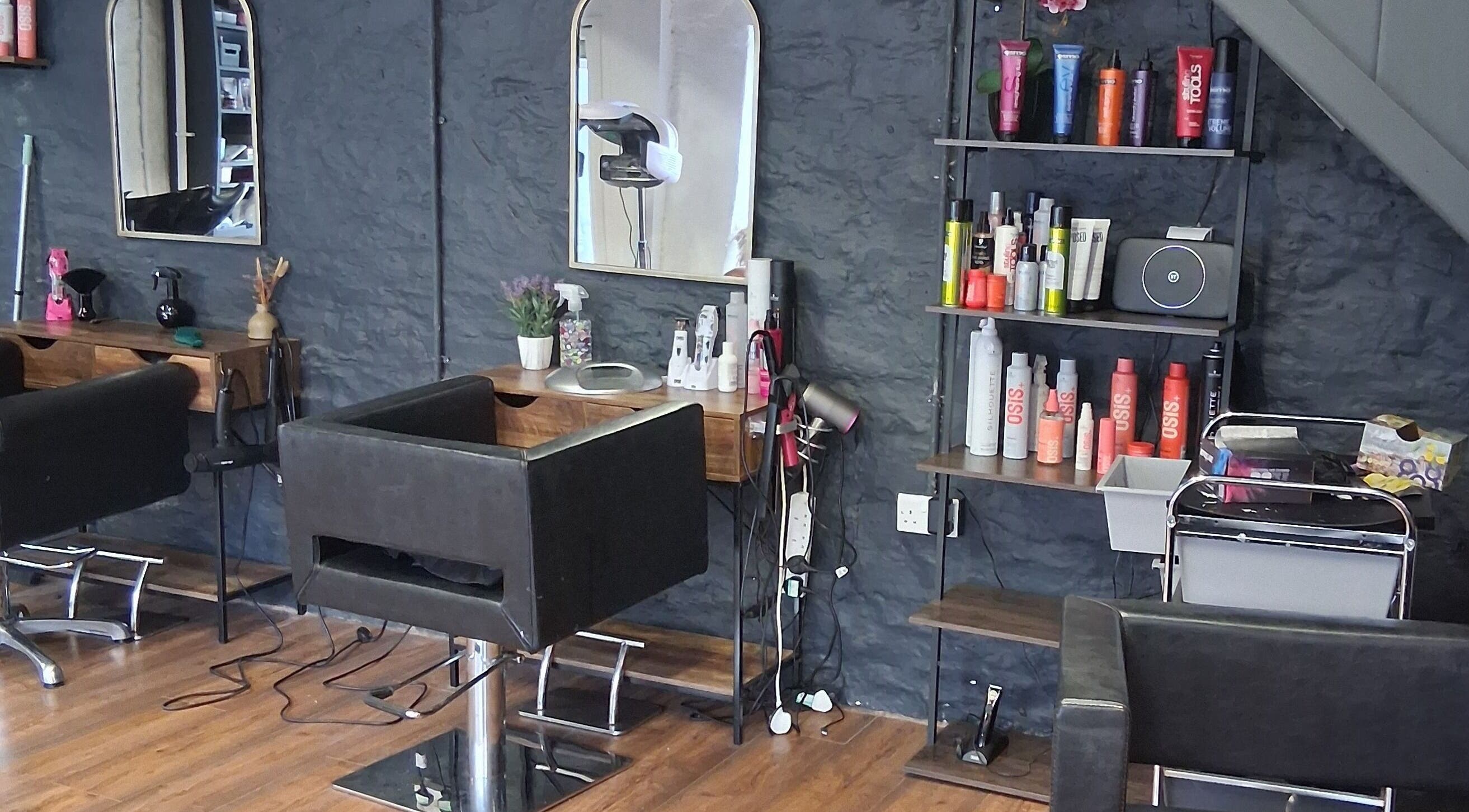 Modern salon interior at Hair By Joy, Lockerbie, Scotland, GB featuring sleek chairs and beauty products.