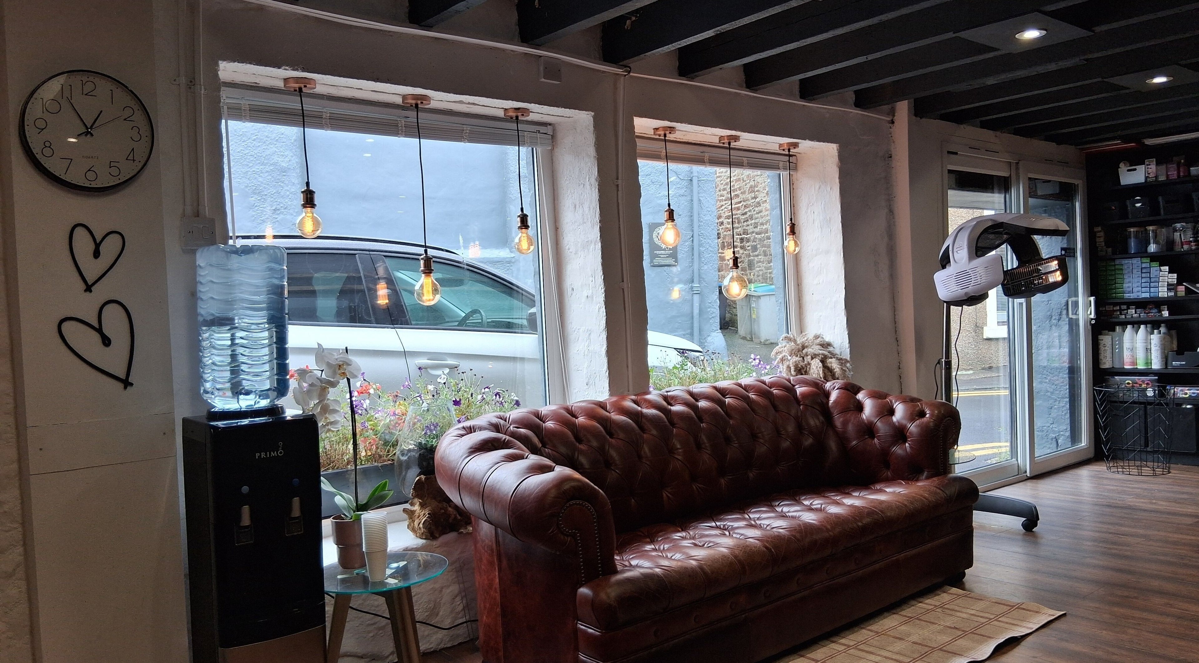 Cozy seating and decor at Hair By Joy, Lockerbie, Scotland, GB with vintage sofa and warm lighting.