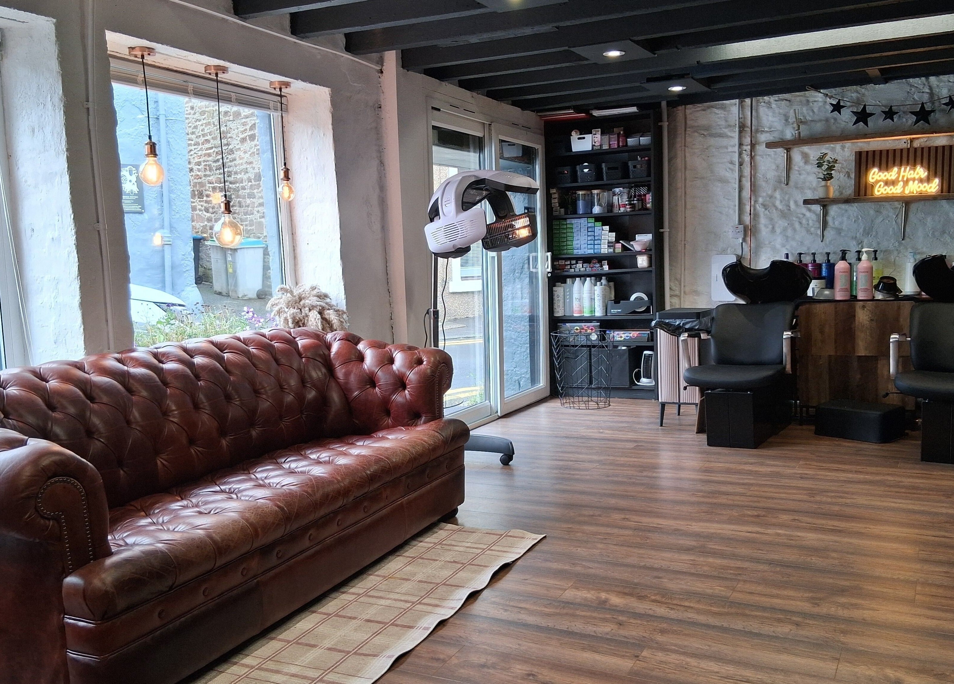 Inviting salon interior at Hair By Joy, Lockerbie, Scotland, GB featuring a leather couch and modern styling area.