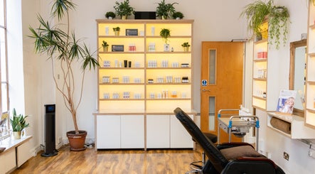 Mg Skincare beauty studio at TOWER BRIDGE LONDON, England. Display shelves with products and green plants.