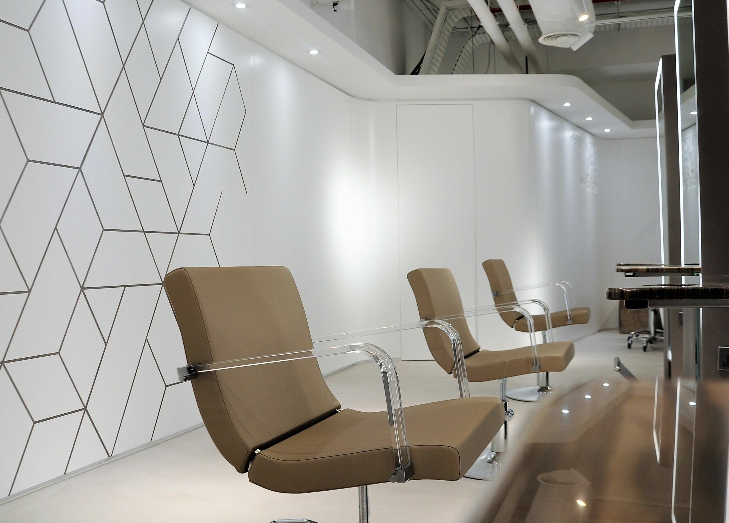 Modern salon seating at Definition - The Hair Expert in Abu Dhabi, Abu Dhabi, AE with sleek geometric wall design.