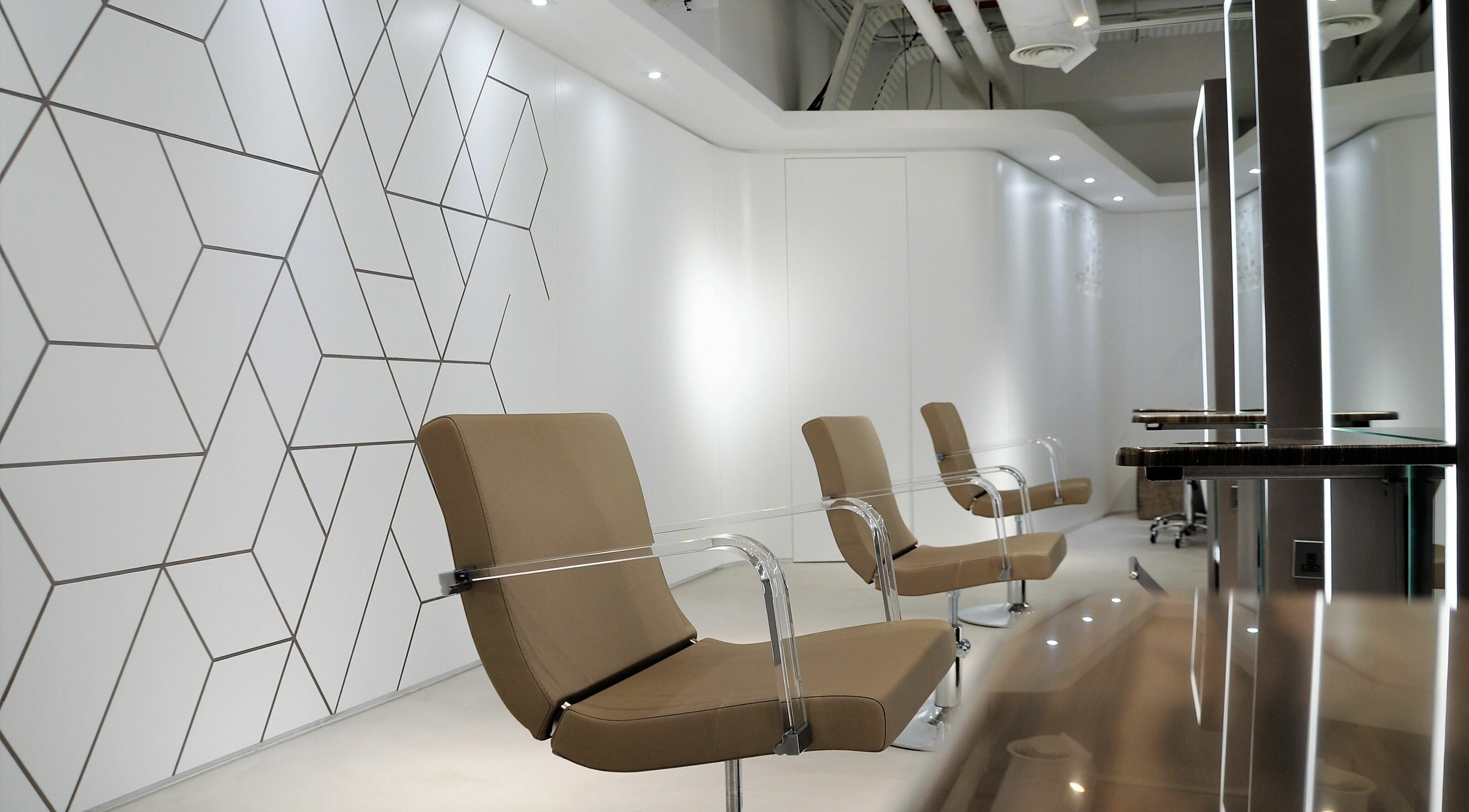 Modern salon seating at Definition - The Hair Expert in Abu Dhabi, Abu Dhabi, AE with sleek geometric wall design.