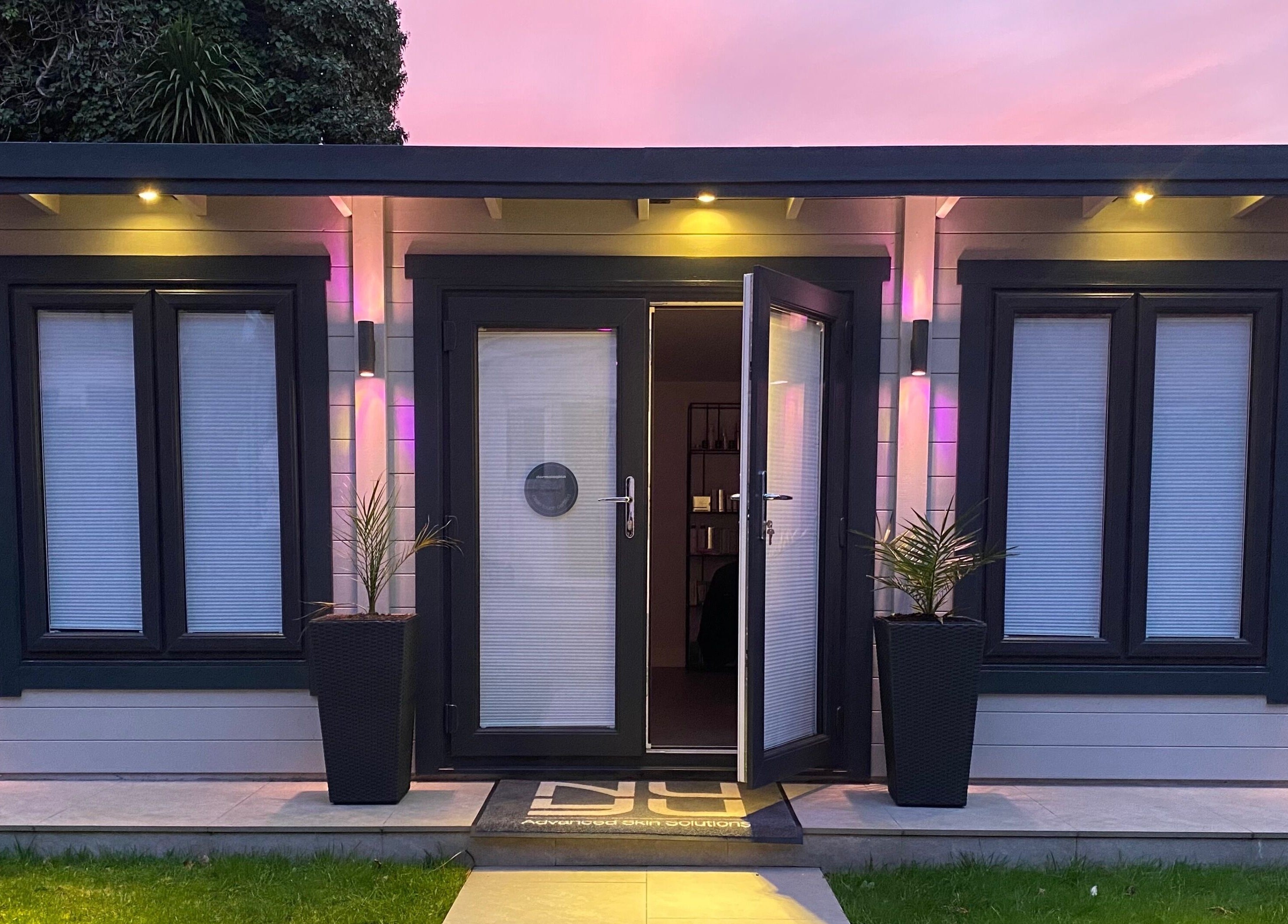 Nu-Yu Advanced Skin Solutions' illuminated entrance in Sidcup, England, GB at dusk with vibrant lighting.