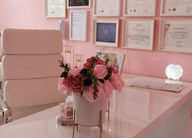 Sala de tratamento elegante do Rostos em Luanda, Luanda, AO com decoração em tons de rosa e certificados nas paredes.