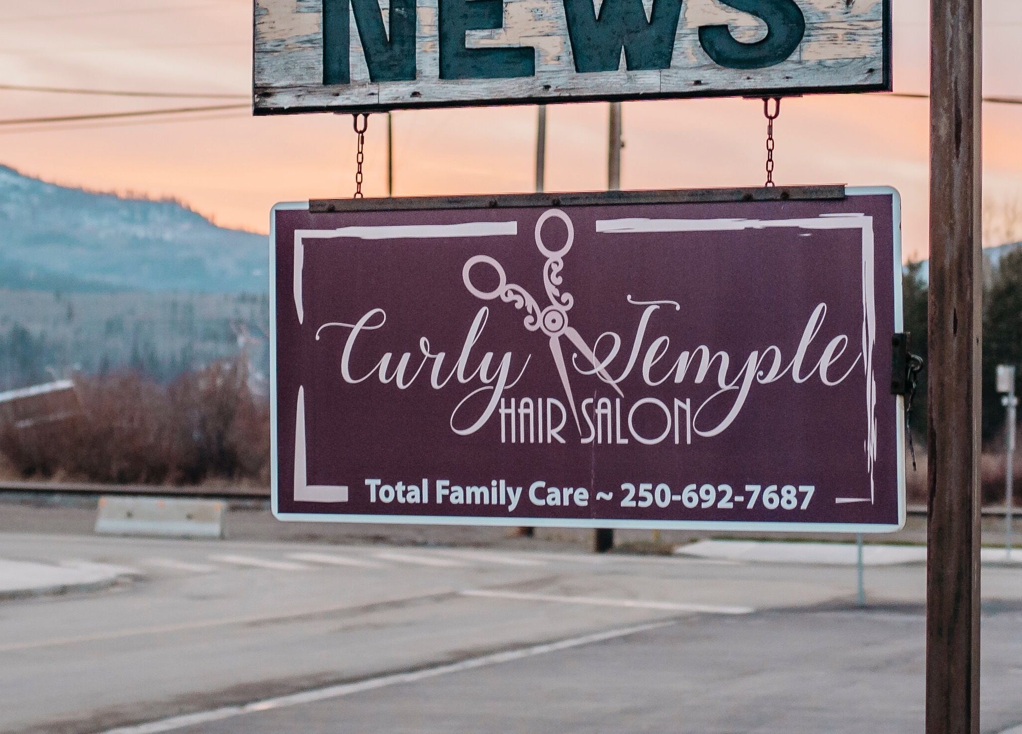 Signboard of The Curly Temple Salon at sunset in Burns Lake, British Columbia, CA.