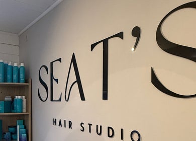 Entrance sign of Seats Hair Studio in Leicester, England, GB with products displayed on wooden shelves.