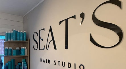 Entrance sign of Seats Hair Studio in Leicester, England, GB with products displayed on wooden shelves.