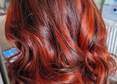 Vibrant red hair styled in waves at Beauty and Hair So Lovely, Braunstone Town, England, GB.