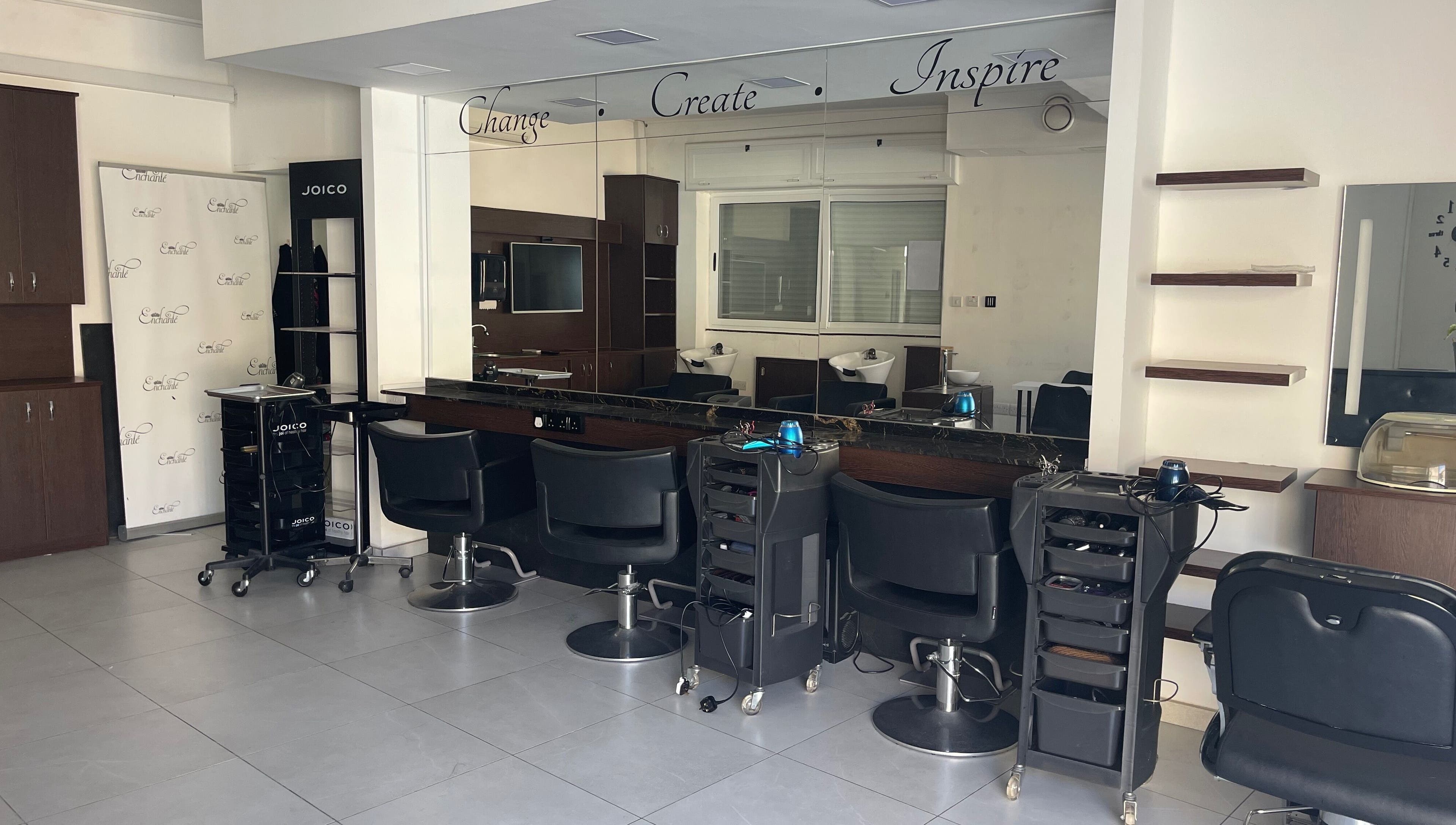Modern salon interior at Enchante Hair Team, Il-mosta, MT, showcasing sleek styling stations and mirrors.