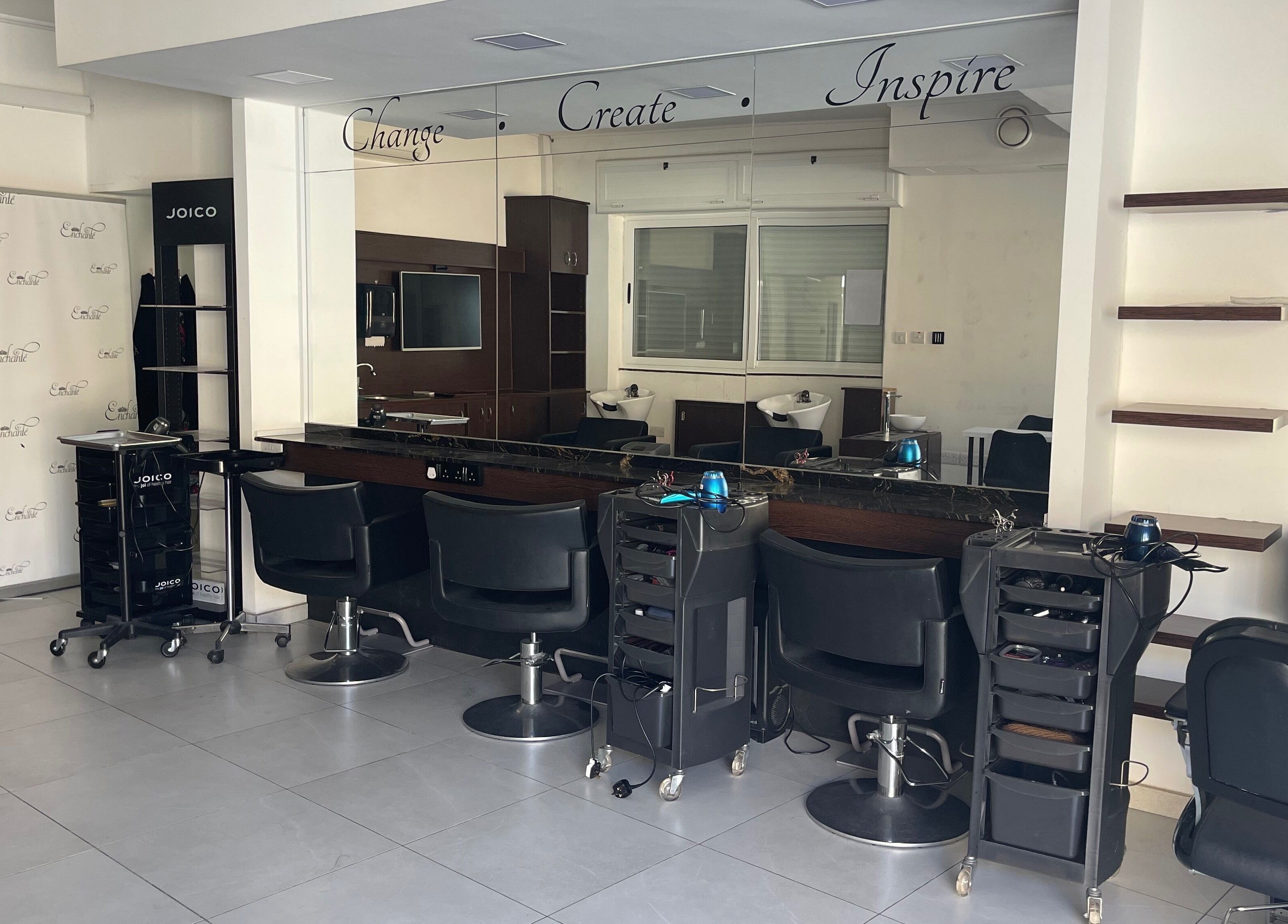 Modern salon interior at Enchante Hair Team, Il-mosta, MT, showcasing sleek styling stations and mirrors.