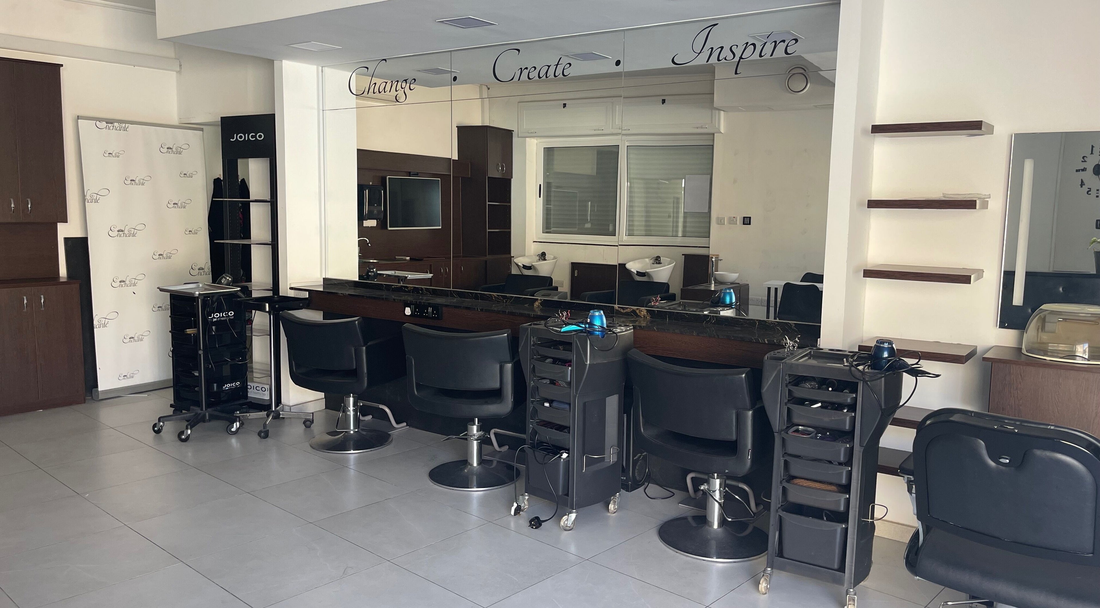 Modern salon interior at Enchante Hair Team, Il-mosta, MT, showcasing sleek styling stations and mirrors.