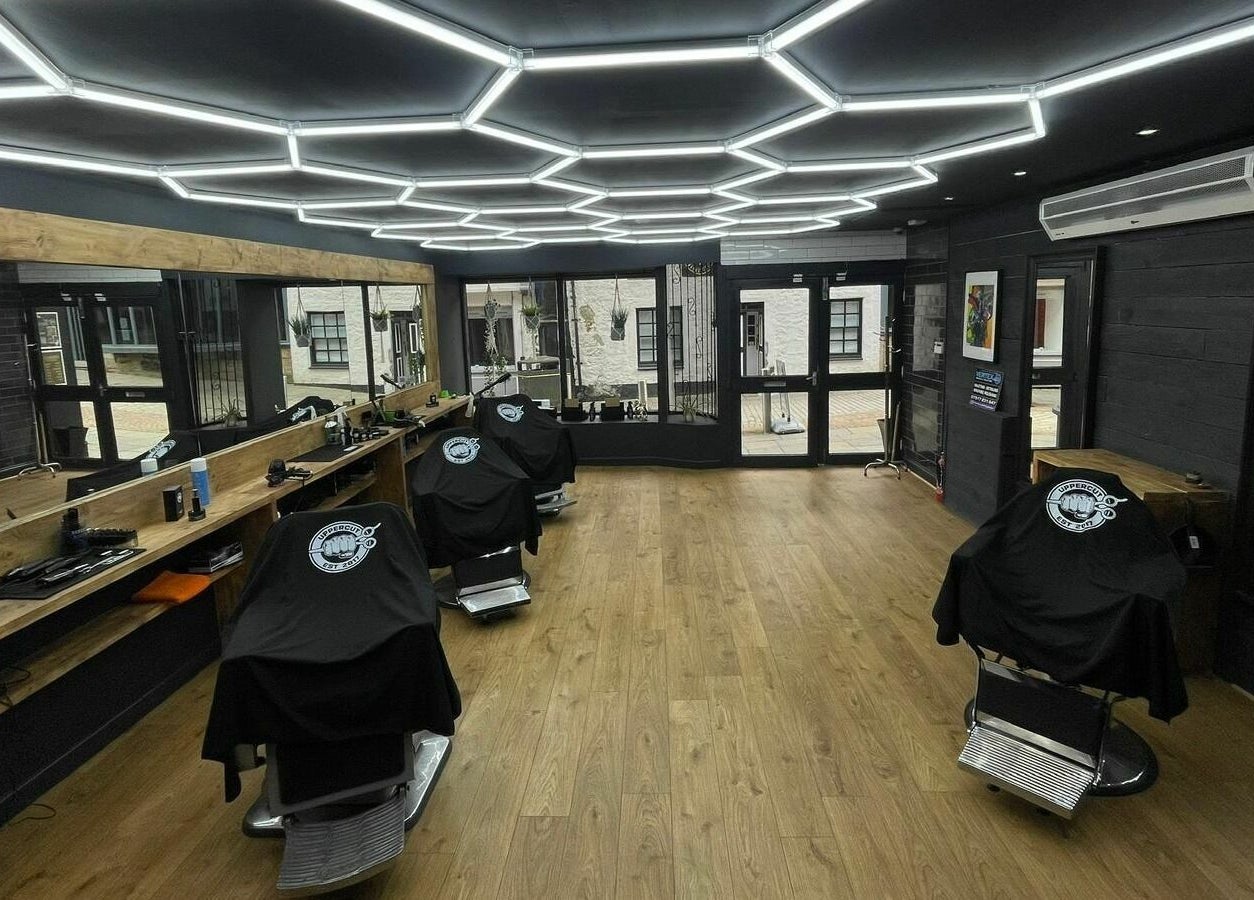 Interior of Uppercut, a sleek barbershop in Kilsyth, Scotland, GB with modern lighting and wooden decor.