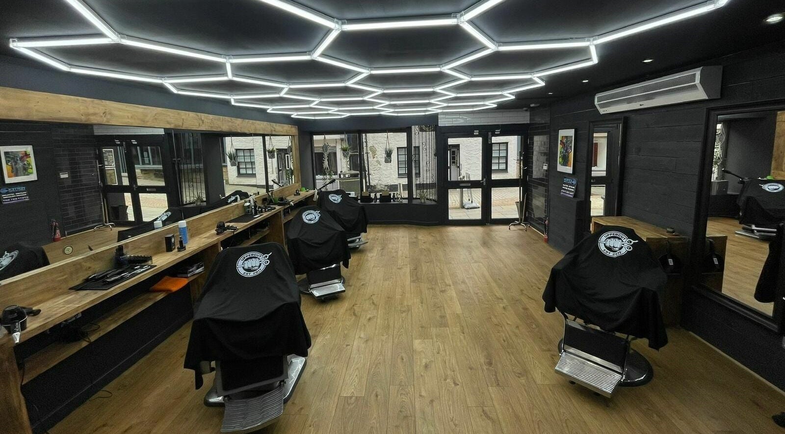 Interior of Uppercut, a sleek barbershop in Kilsyth, Scotland, GB with modern lighting and wooden decor.