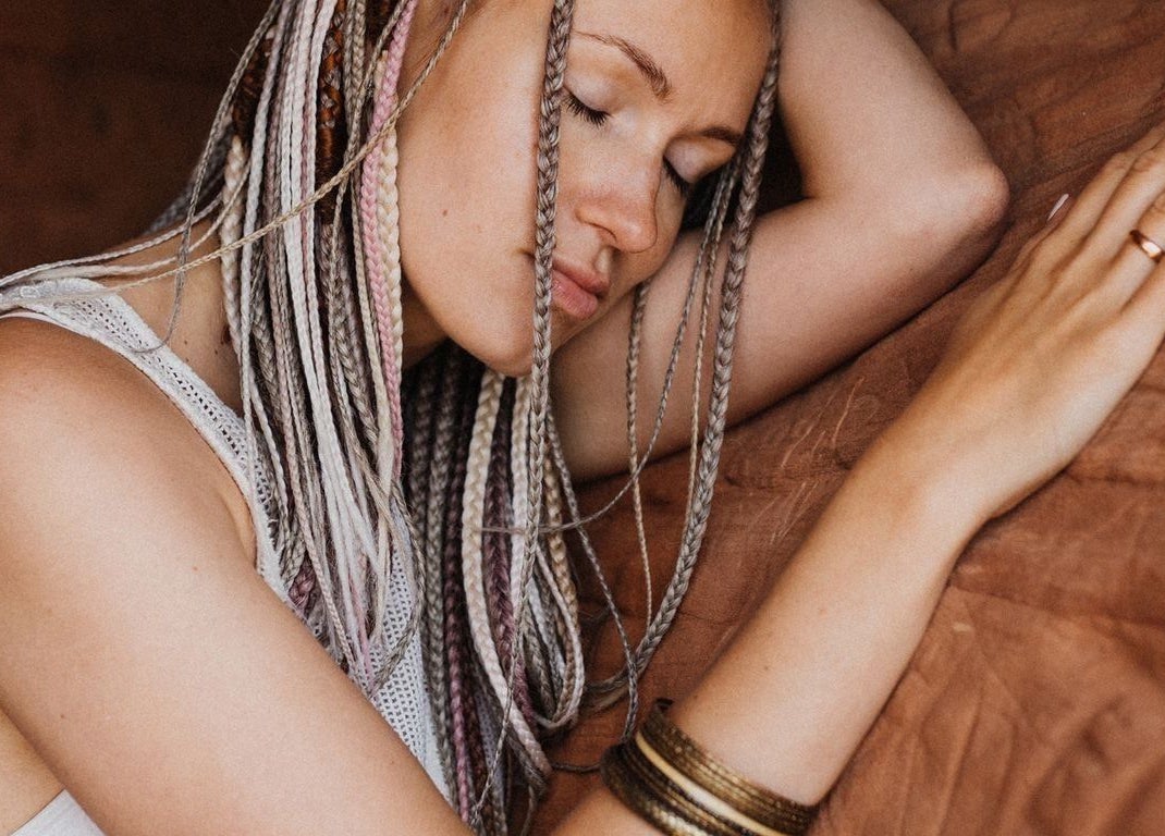 Woman with braids styled at FOXY Braid House, Rīga, LV, resting peacefully.