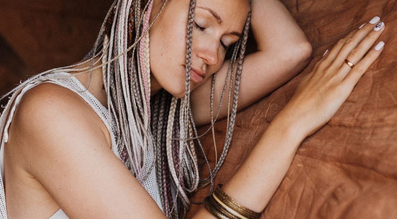 Woman with braids styled at FOXY Braid House, Rīga, LV, resting peacefully.