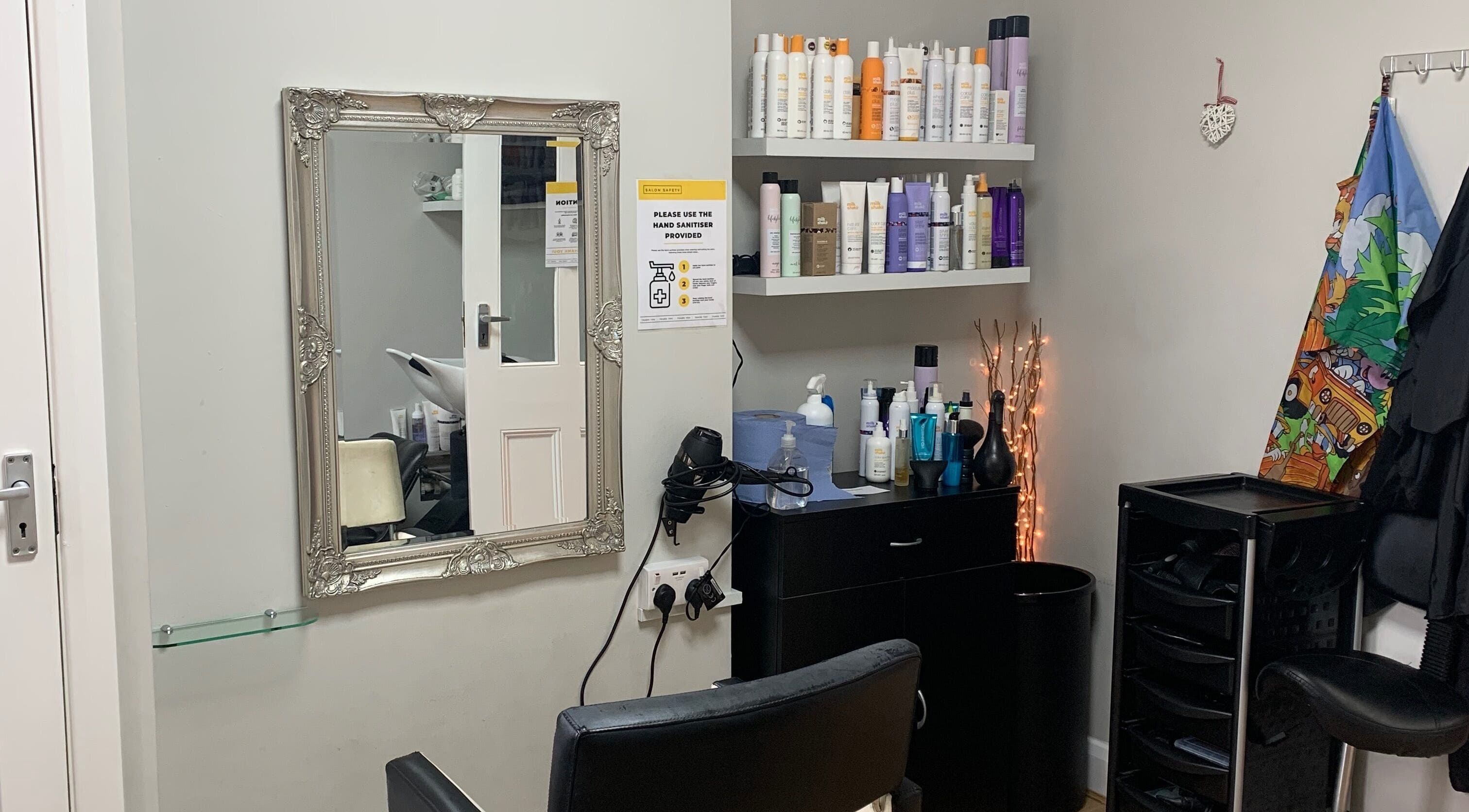 Stylish salon interior at Aron’s Hairdressers, Surbiton, England. Features ornate mirror and haircare products.