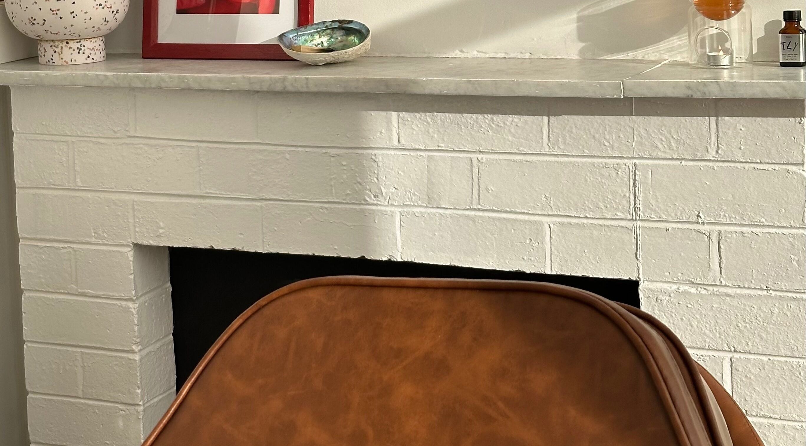 Chic fireplace corner at Néktar Studio, Melbourne, Victoria, AU with decor and cozy chair for relaxation.