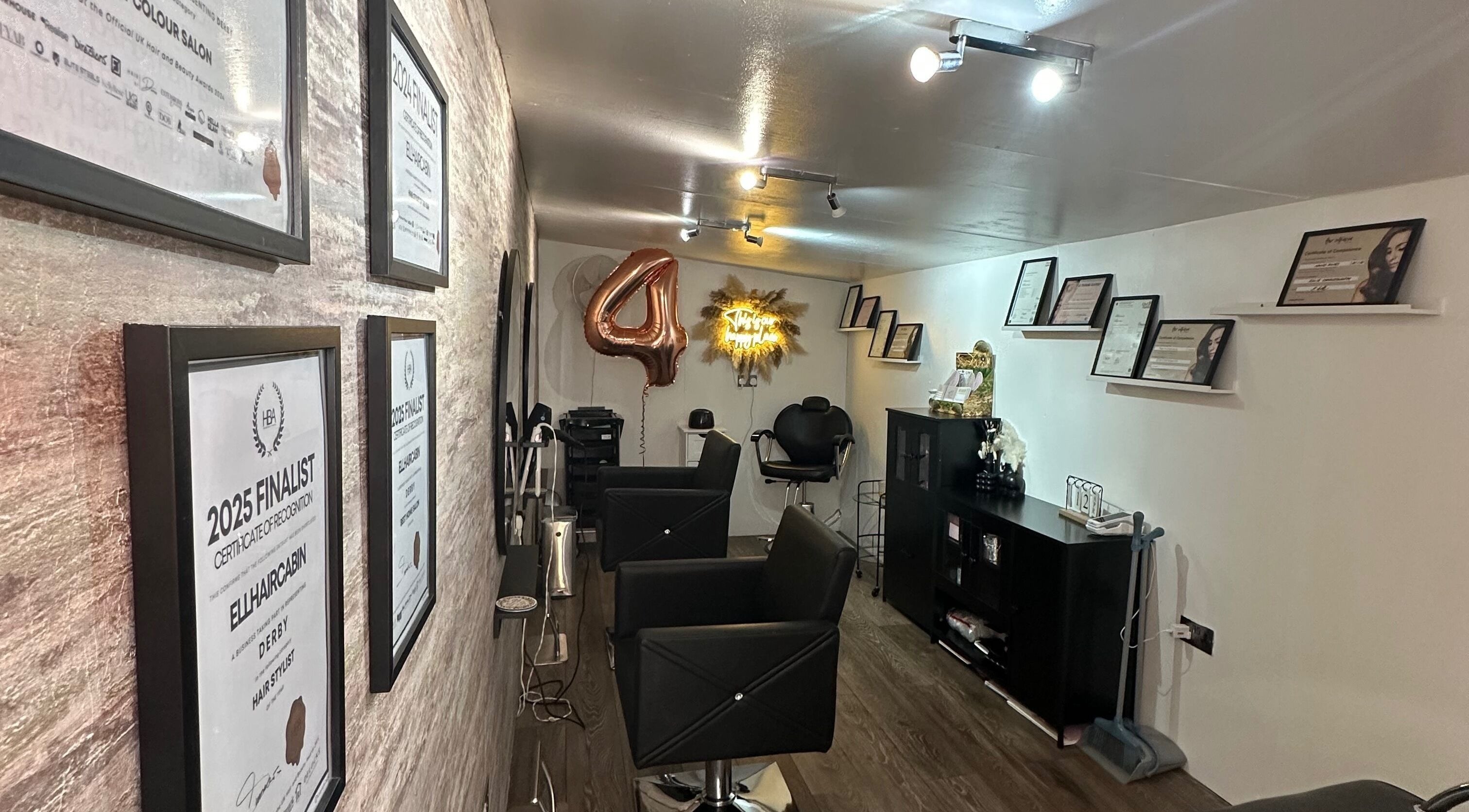 Ellhaircabin interior in Derby, England, showcasing awards and styling chairs in a modern salon setting.
