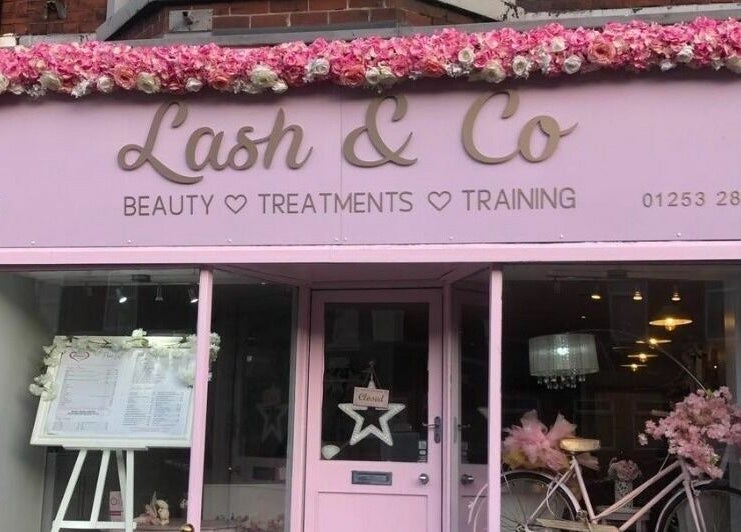 Charming pink storefront of Lash & Co in Fleetwood, England, GB, adorned with flowers and vintage bicycle.