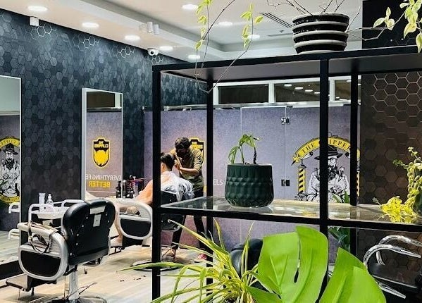 Interior of The Clippers, Cluster Q, JLT in Dubai featuring modern barber chairs and lush plants.