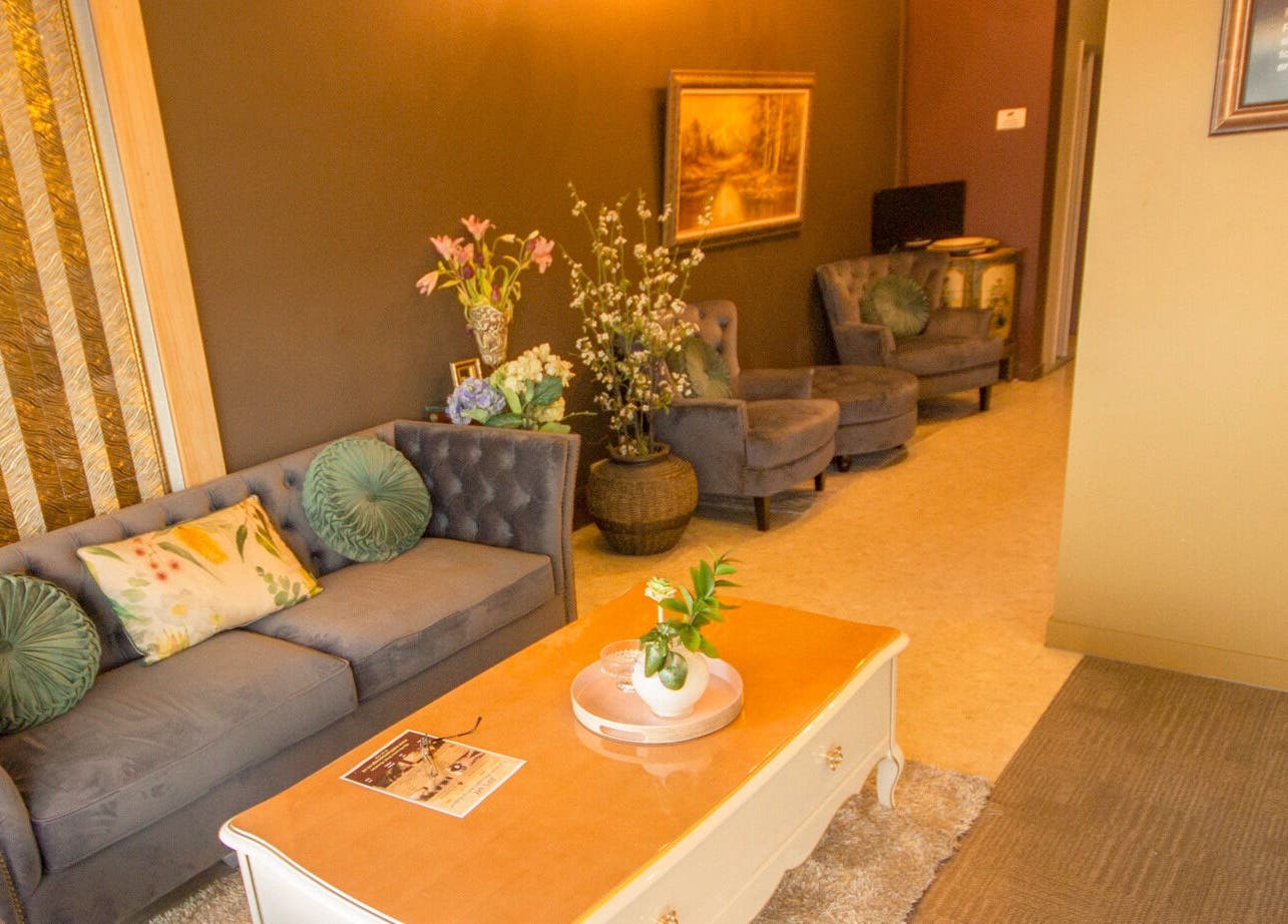 Cozy lounge area at Wai Thai Riccarton, Massage Clinic in Christchurch, NZ, featuring plush sofas and floral decor.