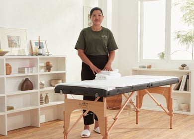 Please Massage in Bangkok, Bangkok, TH: serene massage room with therapist preparing a table.