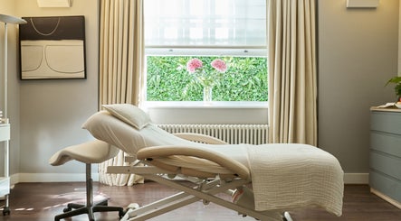 Relaxing treatment room at Wellness at The Laslett, London, England, GB with a massage table and greenery view.