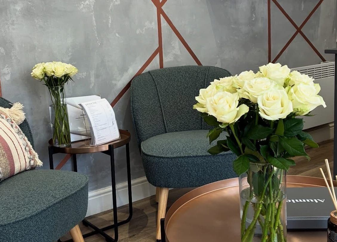Chic lounge at BELÀR esthetics, Disley, England with plush seating and fresh white roses.