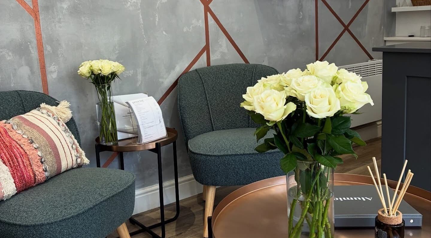 Chic lounge at BELÀR esthetics, Disley, England with plush seating and fresh white roses.