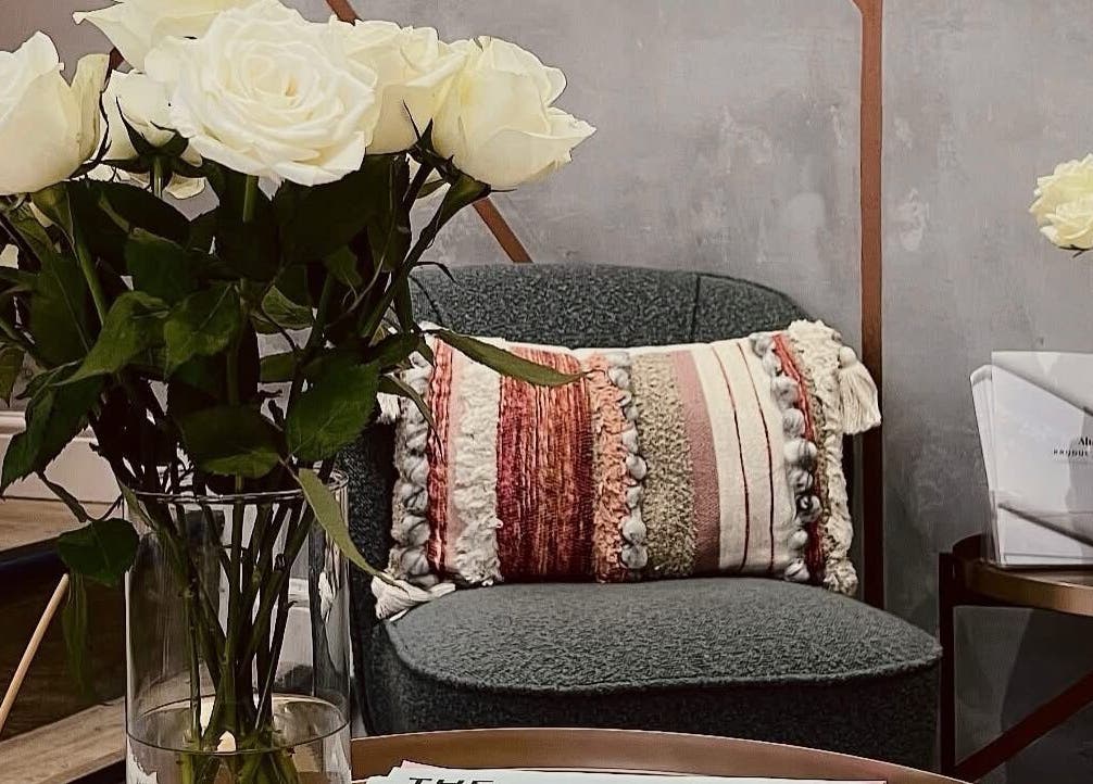 Elegant lounge at BELÀR esthetics, Disley, England adorned with roses and cozy seating.