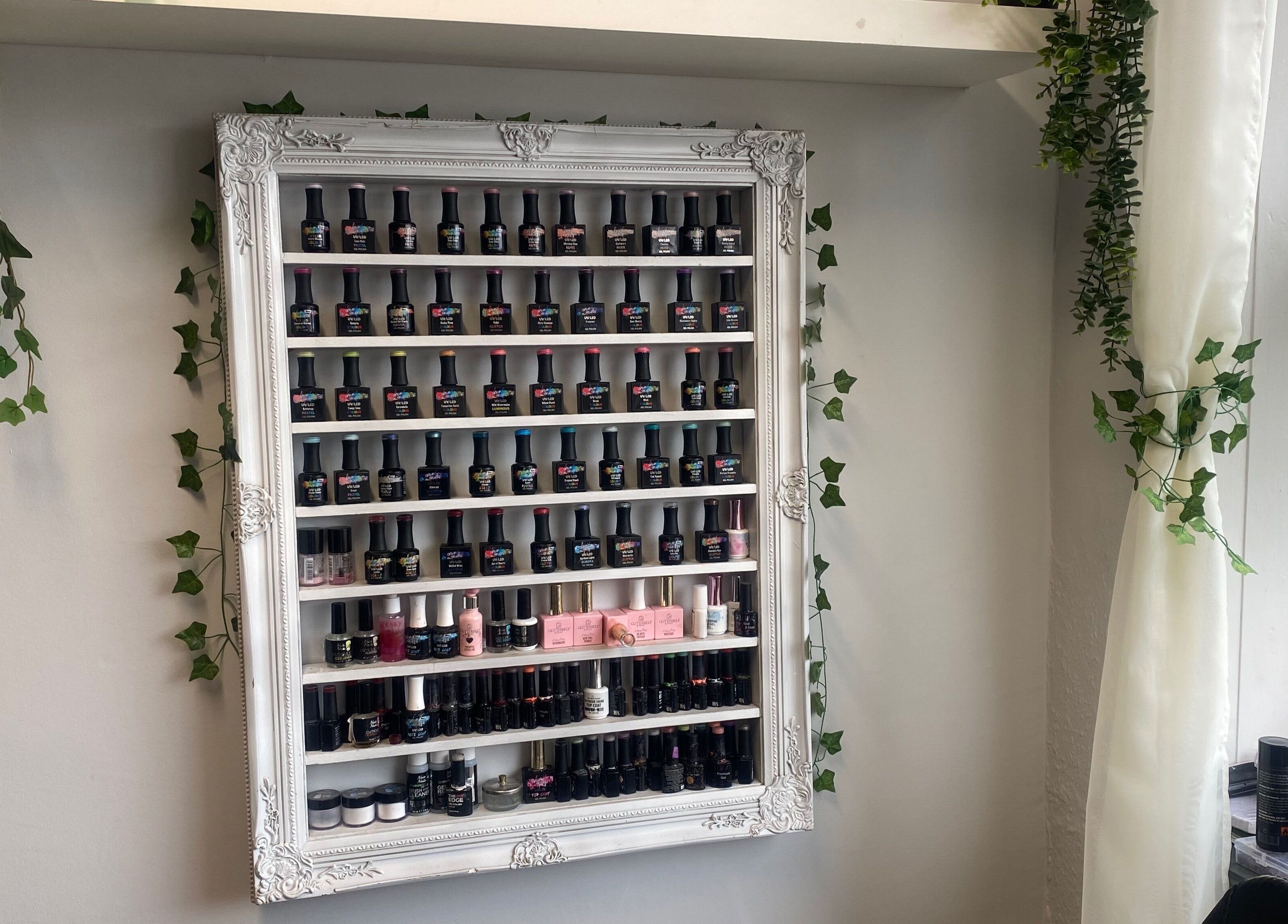 Stylish nail polish shelf at Head to Toe, Grassmoor, England, GB with elegant framing and greenery.