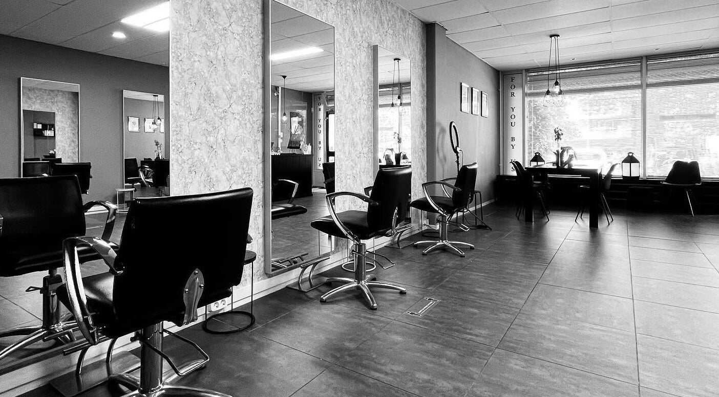 Binnenkant van Yous Krullenspecialist, Almere, Flevoland, NL, met moderne kappersstoelen en spiegels.