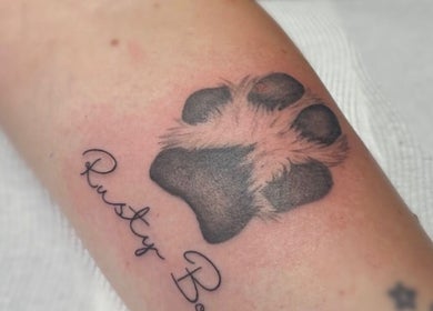 Fineline Tattoos By Carla in Melbourne, Victoria, AU showcases a detailed pawprint tattoo with cursive text.
