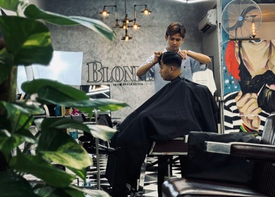 Hairdresser styling a haircut at Blondz Barbershop, Petaling Jaya, Selangor, MY with stylish interior.