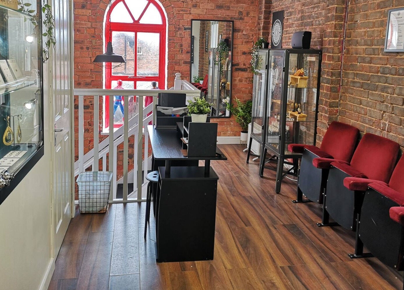 Stylish interior of Arcade Eight Piercing in Newport Pagnell, England, GB with modern decor and red chairs.