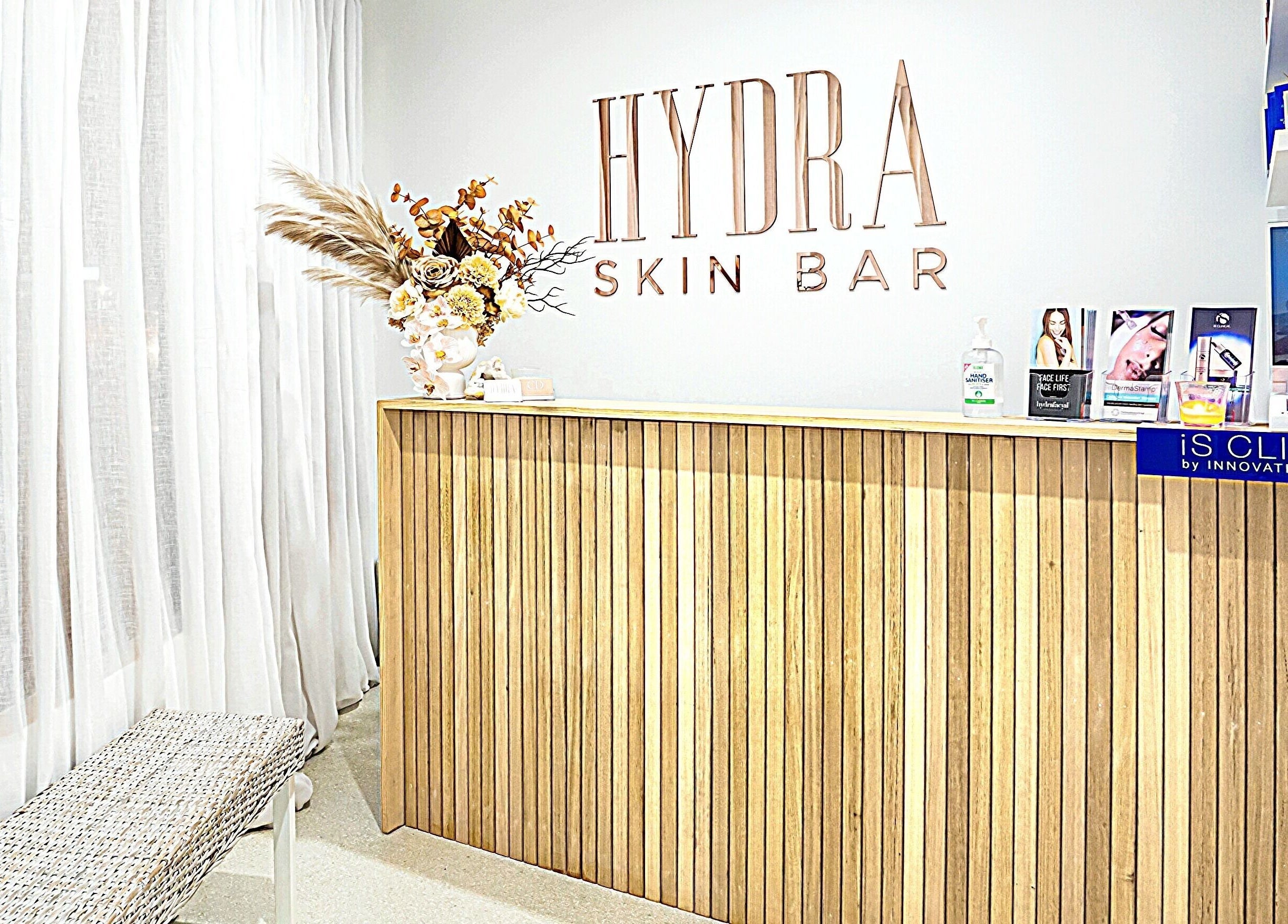 Elegant reception at Hydra Skin Bar in Melbourne, Victoria, AU featuring a modern wooden desk and skincare displays.