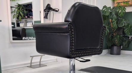 Elegant black salon chair at Hun Hair Bar, Upminster, England, GB with mirror and plant in view.