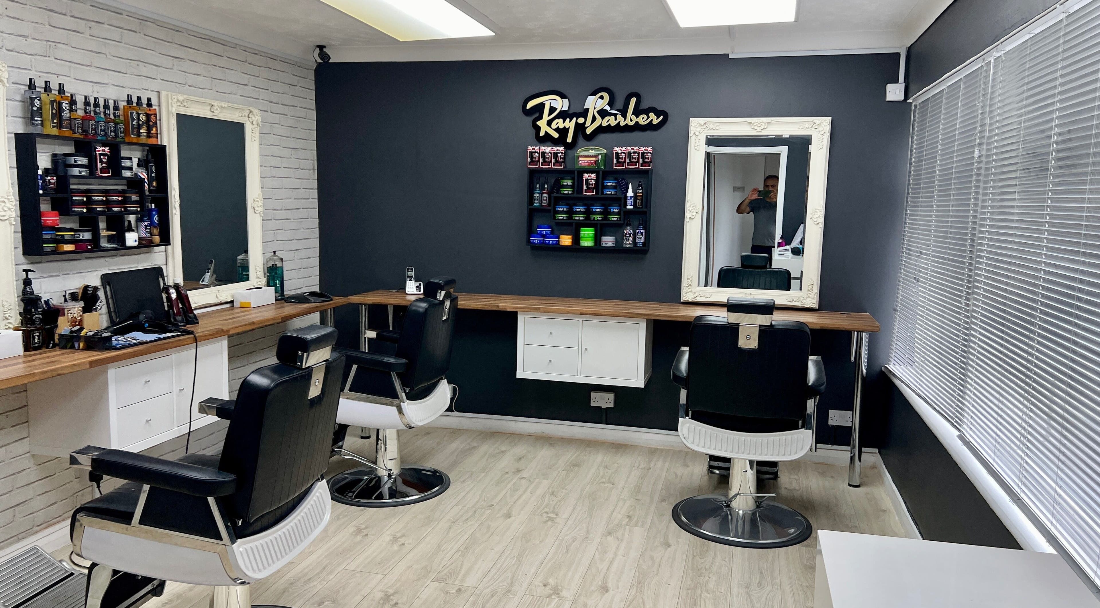 Modern interior of Ray Barbers in Horsham, England, GB, featuring stylish chairs and grooming products.