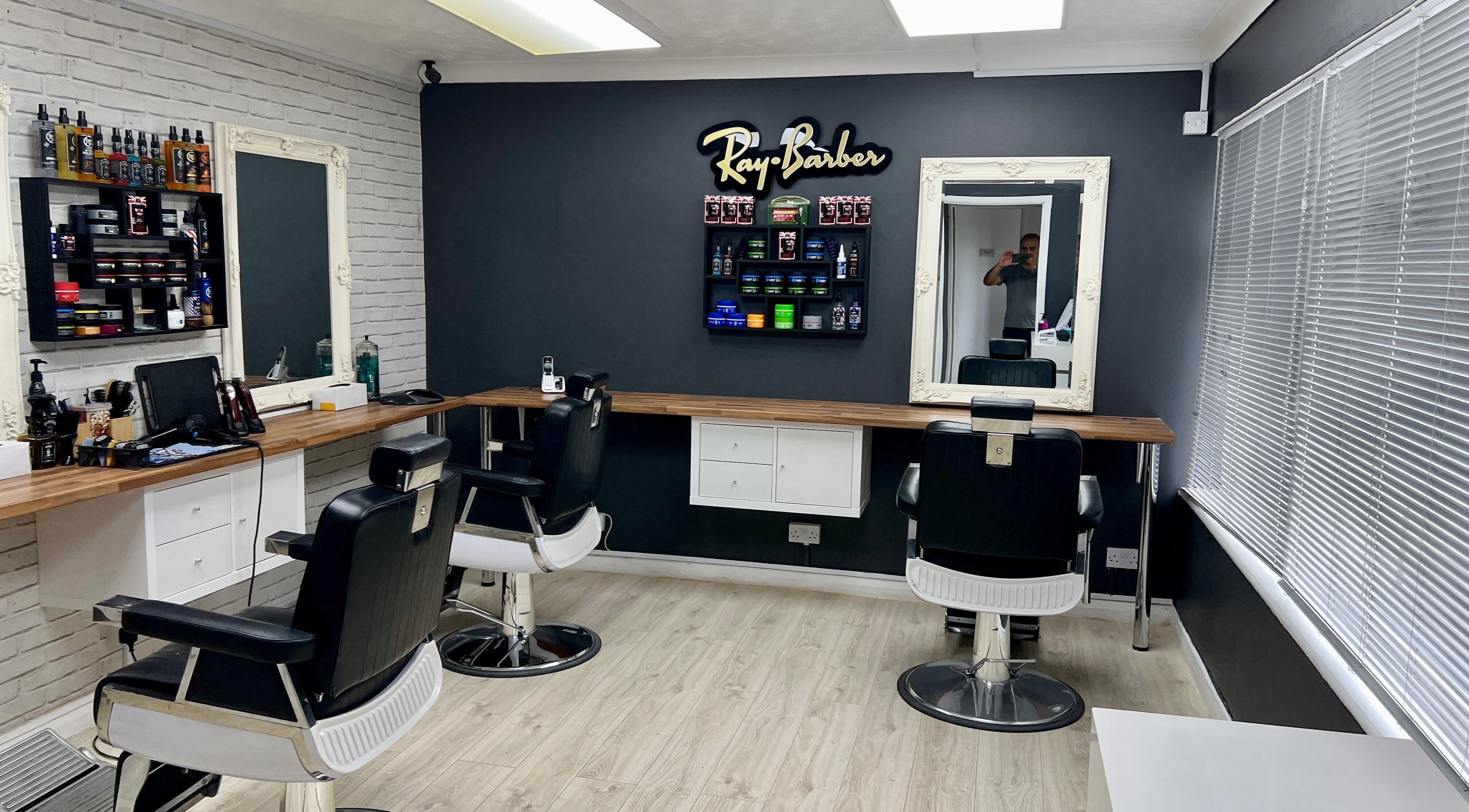 Modern interior of Ray Barbers in Horsham, England, GB, featuring stylish chairs and grooming products.