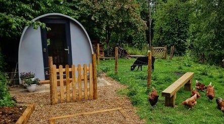 Rustic cabin at Karistyle, Maidstone, England, GB surrounded by lush greenery and peaceful farm animals.
