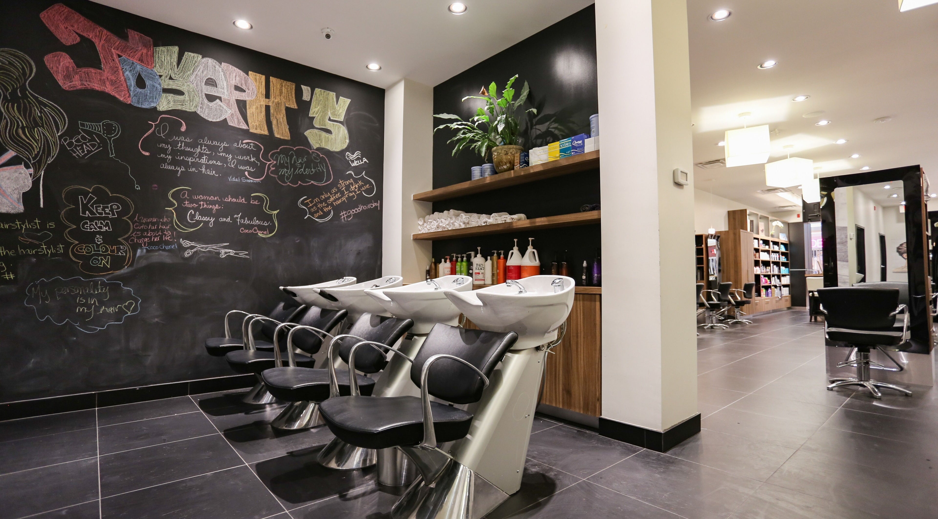 Modern interior of Joseph's Coiffures salon in Ottawa, Ontario, CA with chic black chairs and wall art.