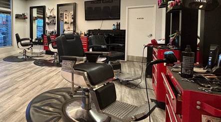Modern interior of Brotherhood Barber Shop Millrise in Calgary, Alberta, CA featuring black chairs and red tool cabinets.