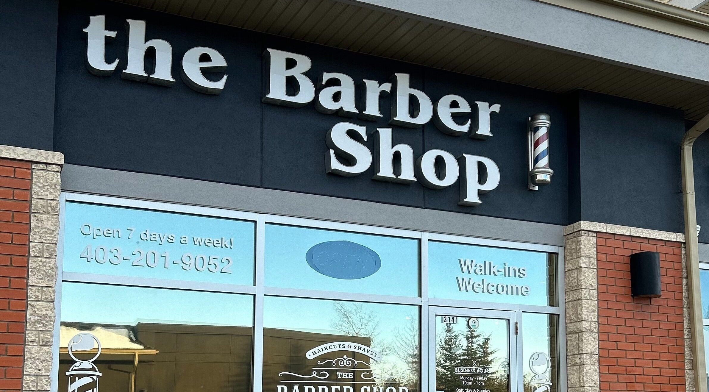 Exterior view of Brotherhood Barber Shop Millrise in Calgary, Alberta, CA with open sign and barber pole.