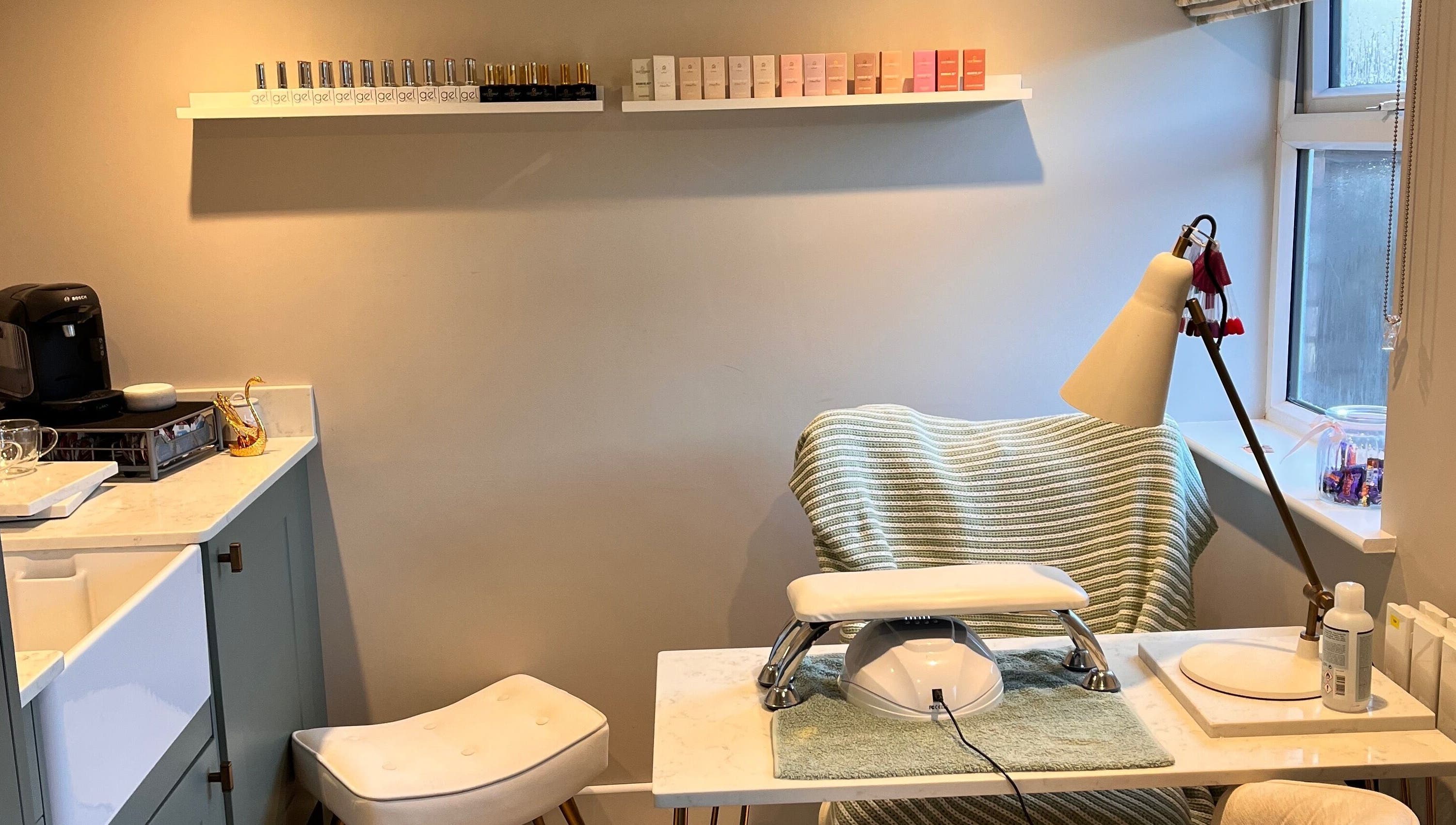 Nail station at Sophie's home salon in Bognor Regis, England, GB, featuring polishes and comfortable seating.
