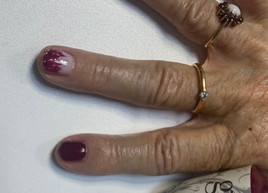 Elegant nail art featuring maroon polish by Mud Beauty in Hook, England, GB. Gold rings enhance the look.