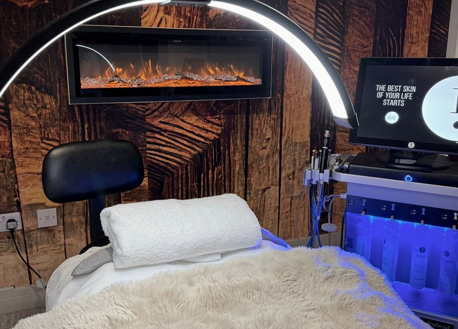 Cozy treatment room at Nu Haven, London, England, GB with a plush bed, modern equipment, and ambient fireplace.