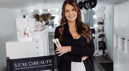 Luxe Beauty studio in Whittlesey, England, GB featuring a smiling woman holding makeup brushes.